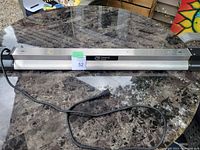 Full view of the 40-inch LED shop light placed on a round table, showing brushed nickel finish and attached power cord.