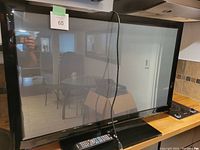 Front view of 42-inch Samsung plasma TV on black stand with remote and power cord visible