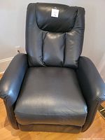 Front view of recliner showing black PU upholstery and lot sticker