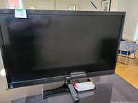 Front view of TV on table with remote and 3D glasses box