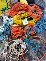 Photo showing a variety of extension cords coiled on a table including large orange and yellow cords and smaller blue and white cords.