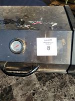 Top view showing stainless steel lid with temperature gauge and handle, worn with scratches.