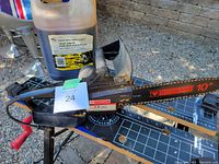 Side profile photo of the Mastercraft electric chain saw on a workbench with container of chain saw oil behind it.
