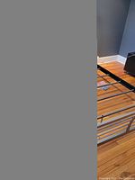 Partial view of the metal bed frame showing horizontal slatted footboard and frame bars on hardwood floor.