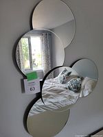 Front view of the five circular mirrors arranged vertically on a grey wall, reflecting a bedroom scene.