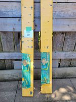 Pair of folded yellow steel sawhorse frames with labels attached, showing paint wear
