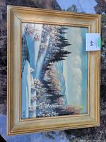 Full view of the framed winter scene painting showing snowy trees, a river, and hills under a cloudy sky.
