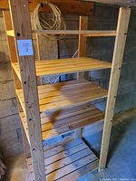 Full view of wooden IKEA shelf showing five slatted shelves and vertical supports in unfinished wood.
