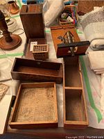 Six antique wood boxes displayed on table along with ship model with cannon