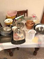 Wide view of assortment of bowls, pans, baking molds and kitchen accessories displayed on a table.