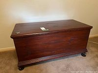 Front view of a vintage wooden blanket box revealing the box surface, shape and color, showing some wear.