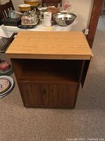 Front view of butcher block showing wooden top, open shelf and lower two-door cabinet.