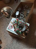 Photo showing metal manual juicer with wooden pestle, box of mason jar lids and screw bands, and multiple mason jars inside a cardboard box.