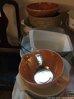 Photo showing a group of kitchenware items including white ceramic CorningWare baking dishes, a woven basket bowl, and a wooden bowl.