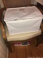 Closed white quilted storage case placed on a chair.