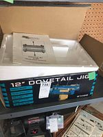 Closed box with label showing '12" Dovetail Jig' and model number W1079, also showing operation manual inside box.