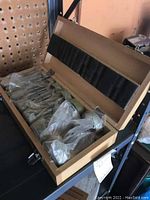 Wooden box containing a set of various size large hole cutting drill bits individually wrapped in plastic.