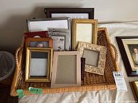 Group of photo frames placed inside a wicker tray basket, various sizes, colors and styles visible