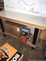 Full view of work table with white laminate top, lower shelf and cardboard lathe box beneath