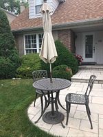 Full exterior view of table, chairs, umbrella and stand on patio
