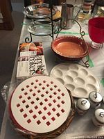 Set of apple pie plates including lattice covered pie plate, deviled egg tray, pie tray and red glass cup on white table cover.