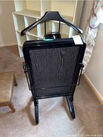 Full view of the folded Bentley electric suit press showing black wooden textured pressing surface and integrated hanger.