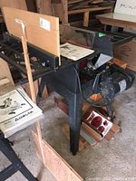 Side view of Craftsman table saw showing motor, metal legs, wooden fence, and instruction manuals on top.