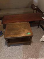 View showing both the wooden coffee table and the side table positioned against a wall, highlighting their size and finish.
