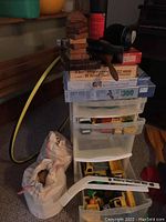 Wide view showing stacked wooden blocks, puzzle boxes, and a plastic storage bin with four drawers, along with a white cloth bag and a hockey stick.