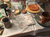 Table with assorted trays, pitchers, ashtrays, and decor items showing variety and details