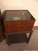 Turntable in closed wooden plinth on stand, showing exterior wood finish and overall size