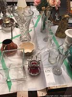 Top view of assortment including cut crystal vase, brass pitcher, ceramic bowl, various glass vases, and colored glass art piece.
