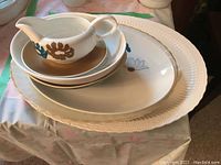 Stacked Wedgwood bone china pieces with floral design and Royal Doulton Desert Star platter underneath