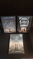Front view of the three DVD covers of Atlas Shrugged trilogy showing parts 1, 2, and 3 with distinct cover art.