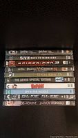 Stack of 10 sealed DVDs with visible titles on spine.