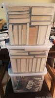 Three stacked plastic bins filled with books, mostly showing their spines and some covers with various sized volumes.