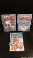 Front view of three DVD cases: Pinky and The Brain Volumes 1 and 2, and Pinky, Elmyra & The Brain complete series.