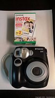 Front view of Polaroid 300 camera with Fujifilm Instax Mini film pack beside it