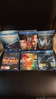 Six sealed Blu Ray cases arranged on a dark surface showing titles: Prometheus to Alien (5 film collection), Arrival, Westworld, Travelers Season One, The Expanse Season Three, and one partially obscured movie.