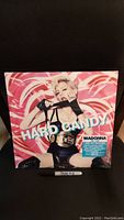 Front cover of Madonna Hard Candy vinyl set featuring Madonna wearing black gloves and championship belt on pink background.
