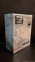 Sealed grey box of The Wire Complete Series DVD set with embossed title and HBO seal sticker on front.