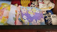Drawer with a variety of vintage aprons in floral, striped, and pastel colors