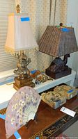 Photo showing two Asian-style lamps with elephant and camel bases, several horse figurines, stone bookends, and a decorative fan displayed on tables.