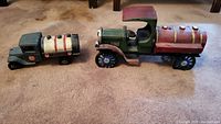 Two cast iron toy trucks side by side on carpet floor, green water truck and Texaco tanker