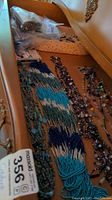 Drawers containing multiple beaded necklaces in shades of blue, purple, and brown.