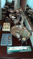 Overview of silverware and serving items including platter, pitcher, cutlery and boxed spoon