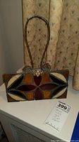 Front view of stained glass style purse decor showing geometric pattern and wire handle.