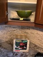 Pyrex nested bowls and three glass cutting boards stacked in cabinet corner, green color bowls visible.