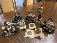 Five Boyds resin figurines displayed on wooden table with four certificates of authenticity included.