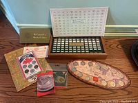 Overview of all items on wooden floor: open ingot case, guidebook, key, coin sets and tokens